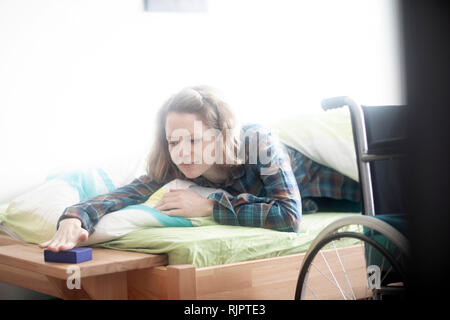 Utilisateur de fauteuil roulant au lit d'arrêter le réveil Banque D'Images