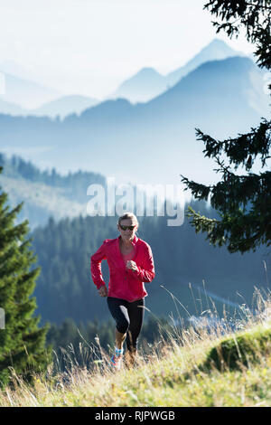 Jogger fonctionnant jusqu'hillside, Manigod, Rhône-Alpes, France Banque D'Images