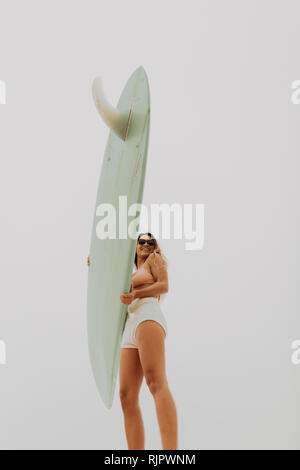 Jeune femme surfer holding surfboard, low angle view, Jalama, Ventura, Californie, USA Banque D'Images