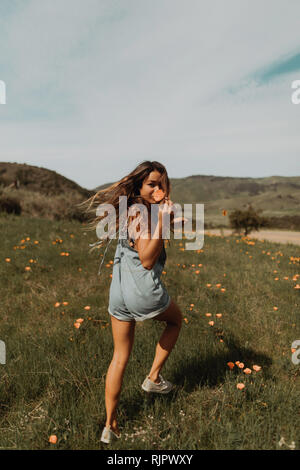 Jeune femme tournant dans le champ de fleurs sauvages, portrait, Californie, Etats-Unis, Jalama Banque D'Images