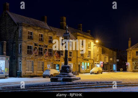 La place du marché Croix avant l'aube dans la neige de l'hiver. Stow on the Wold, Cotswolds, Gloucestershire, Angleterre Banque D'Images