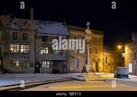La place du marché en face de la Croix le Kings Arms pub avant l'aube dans la neige de l'hiver. Stow on the Wold, Cotswolds, Gloucestershire, Angleterre Banque D'Images