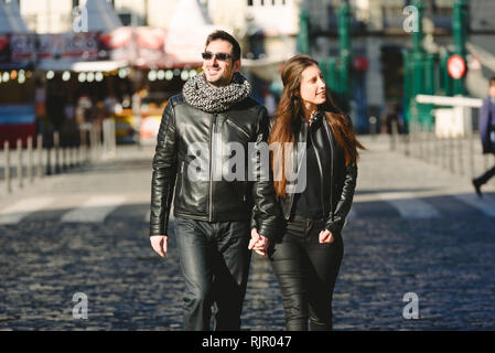 Couple en train de marcher dans le soleil à travers une ville. Banque D'Images