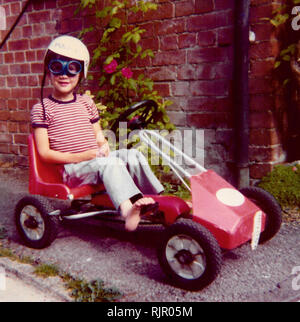 70- Un jeune garçon portant des lunettes et casque assis dans son panier vers 1975 dans le Wiltshire, Angleterre. Banque D'Images