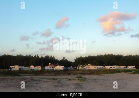 Vue panoramique d'une caravane ou remorque park à proximité de bois en été coucher du soleil avec ciel bleu Banque D'Images