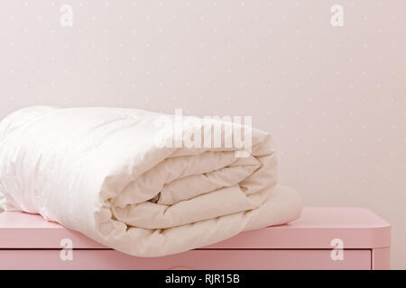 Une couette enroulée est couchée sur la commode. Couverture pour un lit Banque D'Images