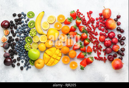 Petits fruits Fruits arc-en-ciel sur fond blanc. Vue de dessus de bleuets fraises mangue cerises citrons oranges pommes prunes mûres Groseilles rouges Banque D'Images