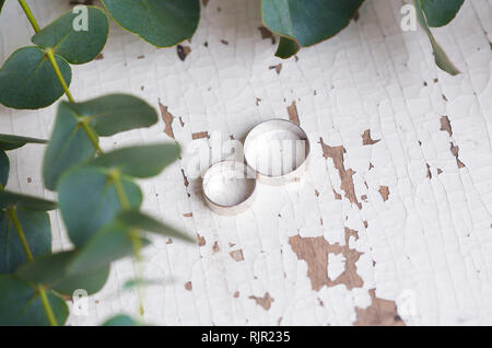 Deux anneaux de mariage sur un tableau blanc avec des branches d'eucalyptus Banque D'Images