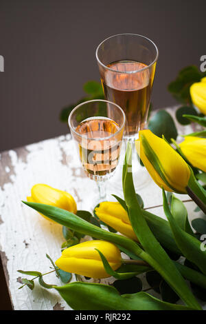 Tulipes jaunes sur un tableau blanc avec un verre de vin rose, close-up Banque D'Images