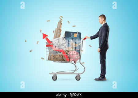 Businessman with panier rempli de sacs d'argent, tirelire, argent, carte bancaire, en toute sécurité avec scyscraper signe dollar et flèche rouge sur bleu backgroun Banque D'Images