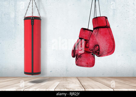 Le rendu 3D de sac de frappe rouge et des gants de boxe sur mur gris et blanc fond de sol en bois Banque D'Images