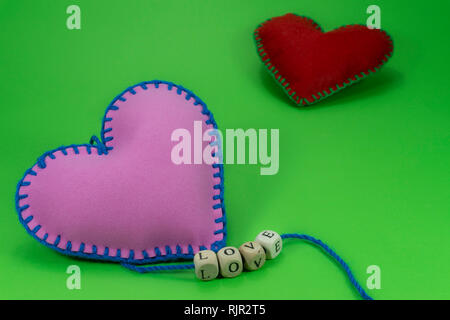 Textile cousu main avec coeurs mot amour sur des cales filetées sur les cordes sur fond vert chromakey pour une relation romantique, Saint Valentin, bro Banque D'Images