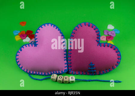 Textile cousu main avec coeurs mot amour sur des cales filetées sur les cordes sur fond vert chromakey pour une relation romantique, Saint Valentin, bro Banque D'Images