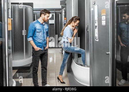 Jeune couple de choisir une nouvelle cabine de douche dans le bâtiment boutique avec des meubles sanitaires Banque D'Images