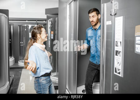 Jeune couple de choisir une nouvelle cabine de douche dans le bâtiment boutique avec des meubles sanitaires Banque D'Images