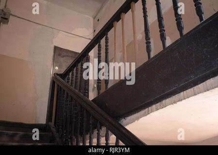 Un escalier conduisant à une pièce d'un bâtiment avec de nouveaux supports de remplacement sur la rampe Banque D'Images