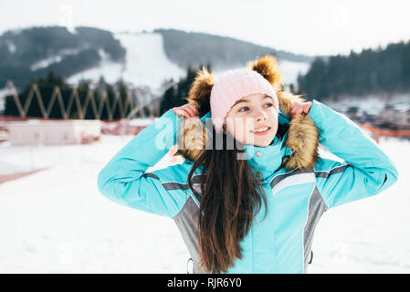 Belle fille dans une veste de ski promenades sur un jour de printemps ensoleillé dans les montagnes Banque D'Images