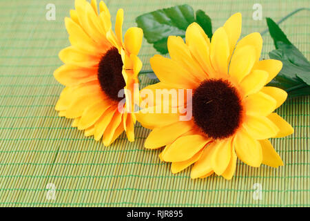 Fleurs en tissu jaune sur fond de bambou, gros plan photo. Banque D'Images