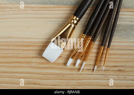 Un ensemble de brosses synthétiques pour l'acrylique et huile allongé sur une planche en bois Banque D'Images