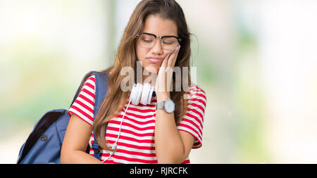 Jeune étudiante belle brunette woman wearing headphones et son sac à dos sur fond isolé à la pensée fatigué et ennuyé avec la dépression problèmes Banque D'Images