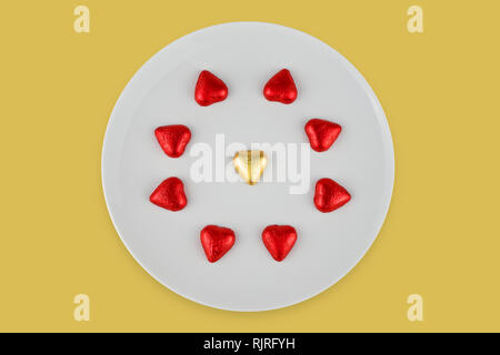 Résumé au chocolat en forme de coeur sur plaque blanche isolé sur fond jaune. Carte de voeux pour fêter la Saint-Valentin Banque D'Images