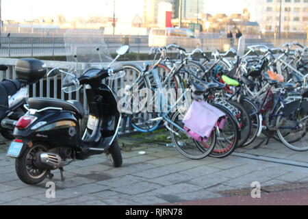 Scooter cyclomoteur noir garé à côté de bicyclettes dans Amsterdam, Pays-Bas Banque D'Images