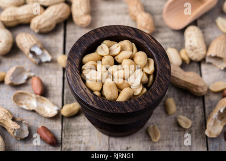 Les arachides dans de petits bol en bois sombre naturel sur le bureau rustique. Banque D'Images