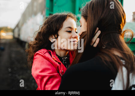 Homme aux cheveux longs embrassant et embrassant la femme près du train Banque D'Images