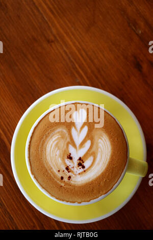 Tasse de cappuccino avec latte art sur une table en bois brun rouge Banque D'Images
