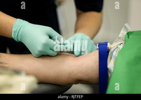 Les détails avec les mains d'un médecin, le port de gants de chirurgie en caoutchouc, préparation à la prise de sang de la veine d'un patient avec un cathéter Banque D'Images