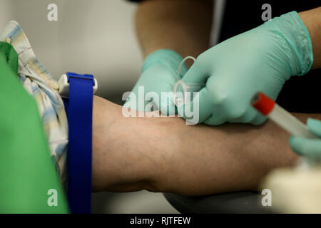 Les détails avec les mains d'un médecin, le port de gants de chirurgie en caoutchouc, préparation à la prise de sang de la veine d'un patient avec un cathéter Banque D'Images
