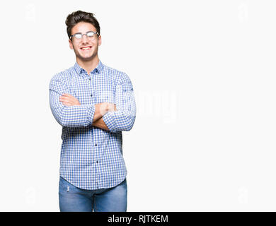 Beau jeune homme portant des lunettes au fond isolé heureux face smiling avec bras croisés regardant la caméra. Personne positive. Banque D'Images