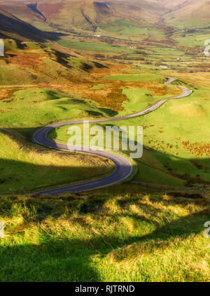 La route serpente à travers une fente, entouré d'immenses pinacles calcaires près de passage winnat, Peak District, UK. Banque D'Images