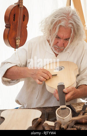 Le luthier travaillant sur la création d'un instrument à cordes. Divers outils et instruments sont placés sur l'établi Banque D'Images