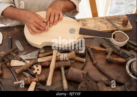 Le luthier travaillant sur la création d'un instrument à cordes. Divers outils et instruments sont placés sur l'établi Banque D'Images