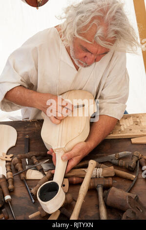 Le luthier travaillant sur la création d'un instrument à cordes. Divers outils et instruments sont placés sur l'établi Banque D'Images