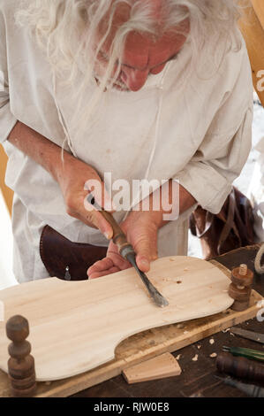 Le luthier travaillant sur la création d'un instrument à cordes. Il utilise un burin pour sculpter le haut. Banque D'Images