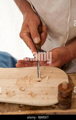 Le luthier travaillant sur la création d'un instrument à cordes. Il utilise un burin pour sculpter le haut. Banque D'Images