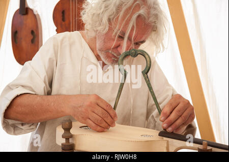 Le luthier travaillant sur la création d'un instrument à cordes. Il utilise un grand compas pour prendre la mesure exacte Banque D'Images