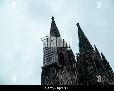 Coup du gothique minimaliste de la cathédrale de Cologne en Allemagne avec l'échafaudage contre ciel nuageux Banque D'Images