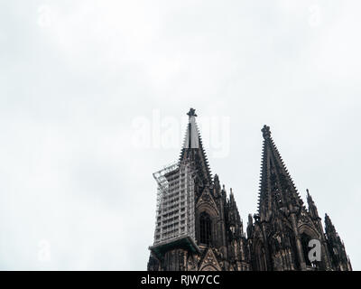 Coup du gothique minimaliste de la cathédrale de Cologne en Allemagne avec l'échafaudage contre ciel nuageux Banque D'Images