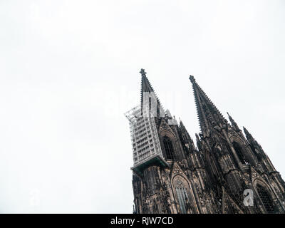 Coup du gothique minimaliste de la cathédrale de Cologne en Allemagne avec l'échafaudage contre ciel nuageux Banque D'Images