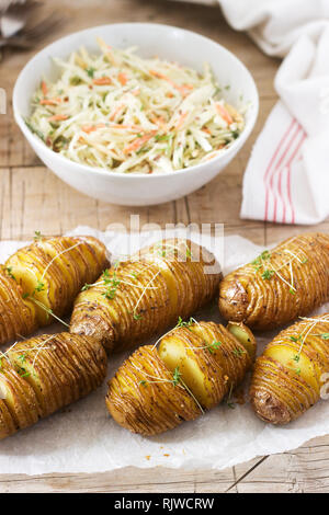 La nourriture végétarienne, hasselback pommes de terre avec la sauce et la salade de chou sur un fond de bois. Style rustique. Banque D'Images