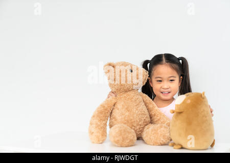 Belle jeune fille asiatique jouant avec 2 poupées en peluche mignon à la maison, l'espace de copie sur mur blanc arrière-plan. Un jeu d'enfant, de la petite enfance jeunesse activité Banque D'Images