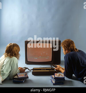 Accueil Les jeux vidéos dans les années 80. Une console de jeux vidéo accueil de Intellivison publié par Mattel Electronics en 1979. Sur la photo deux personnes jouant un jeu sur un téléviseur. ref BV97-5 Banque D'Images