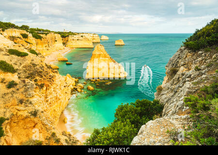 Bateau naviguant sur la mer par des falaises et des formations rocheuses, vue de haut niveau, Praia da Marinha, Algarve. Le Portugal, l'Europe Banque D'Images