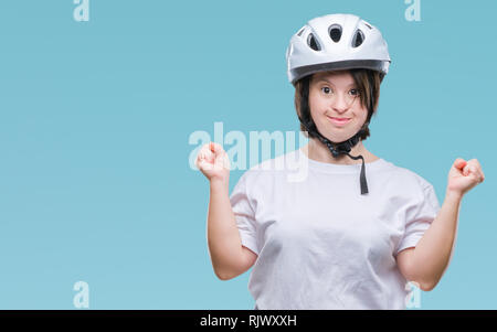 Les jeunes cyclistes adultes femme avec le syndrome de porter un casque de sécurité sur fond isolé et fou fou célèbre pour le succès avec bras levés et Banque D'Images