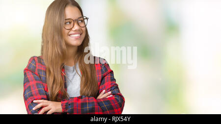 Jeune belle brunette woman wearing jacket et verres sur fond isolé à sourire sur le côté avec les bras croisés convaincu et se confient Banque D'Images