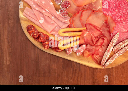 Charcuterie gastronomique. Gros plan d'une photo prise à la verticale d'un bac avec beaucoup des saucisses et jambons, charcuterie, tourné à partir de ci-dessus sur une rustique en bois foncé retour Banque D'Images