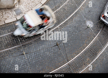 Rue pavée de Lisbonne antenne avec voies de tram et aller de l'un scooter. Banque D'Images